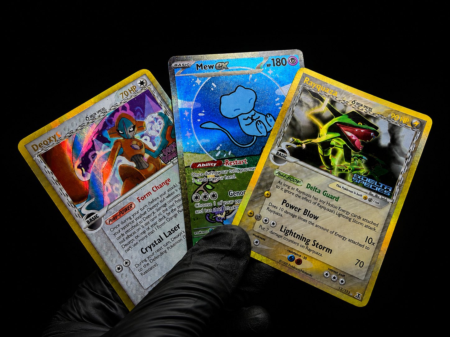 Gloved hands holding several trading cards against a black background